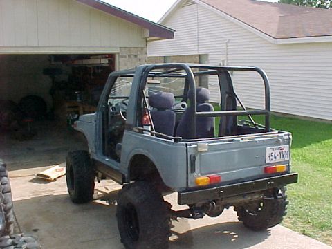 1978 Ford Bronco - This Suzuki Samurai has a roll cage and is lifted with large tires. It is parked in front of a garage.