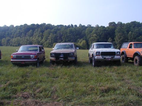 1988 Ford Bronco - A white 1978 Ford Bronco is parked in a field with three other SUVs, one of which has a "BIG BRONCO CLUB" sticker on its windshield.