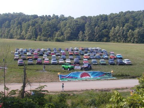 1988 Ford Bronco - A large group of SUVs and trucks are gathered in a field, with a banner indicating a 'Free 4 All' event.