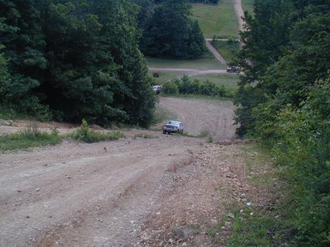 1988 Ford Bronco - A white SUV navigates a steep dirt road, with another vehicle visible further up the hill.