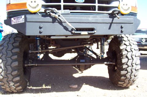 1992 Ford Bronco - Front view of a 1992 Ford Bronco, showing off-road modifications and a custom bumper. Another vehicle is parked nearby.