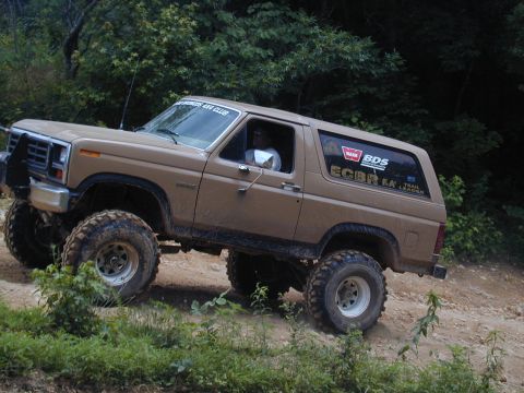 1988 Ford Bronco - 1988 Ford Bronco navigates a challenging off-road trail with its lifted suspension and aggressive tires.