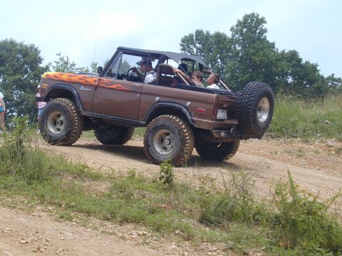 1988 Ford Bronco - This lifted 4x4 Bronco is equipped for off-road adventures, a flame decal on the hood and a spare tire mounted on the rear.