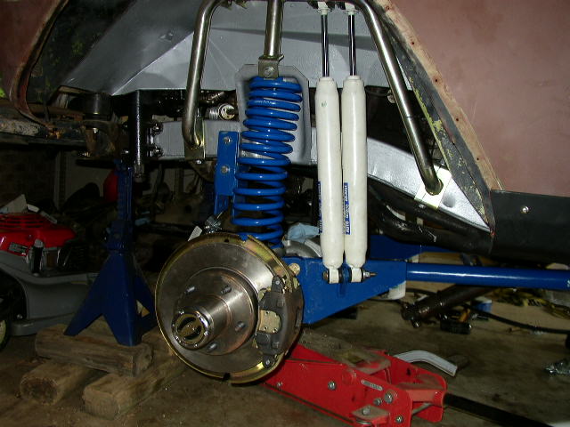 close-up of vehicle's front suspension with blue coilover shocks and brake rotor