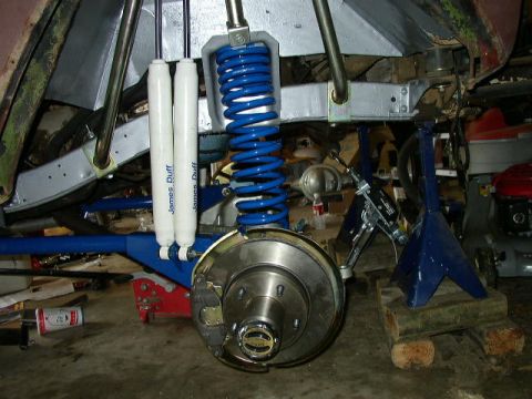 1995 Ford Bronco - The rear suspension of a vehicle is shown, blue coilover shocks and a disc brake assembly. James Duff shocks are clearly labeled.