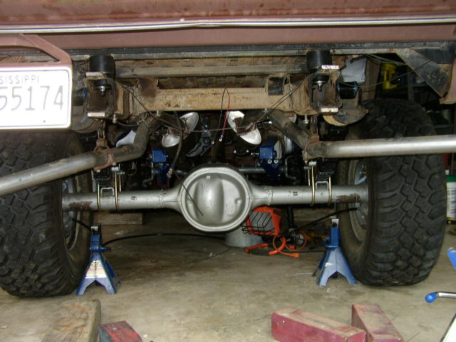 Rear axle assembly with suspension components and large tires, vehicle supported by jack stands