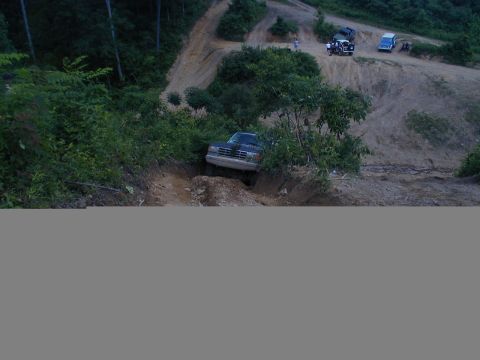1988 Ford Bronco - A truck navigates a challenging off-road trail while other vehicles observe from higher ground.