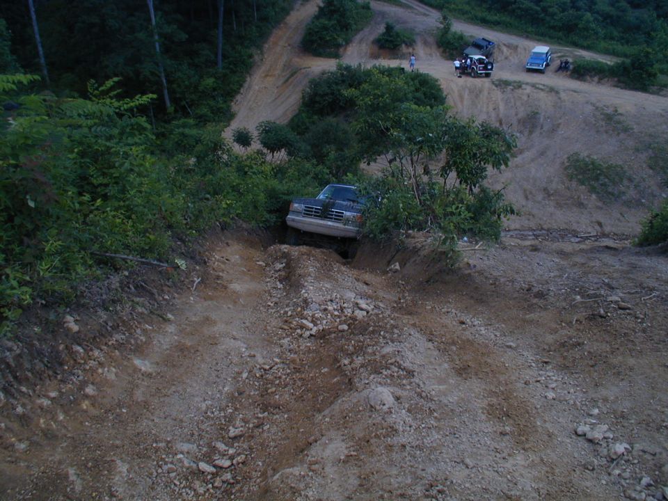 Dark SUV descending rocky trail; 1990s body style