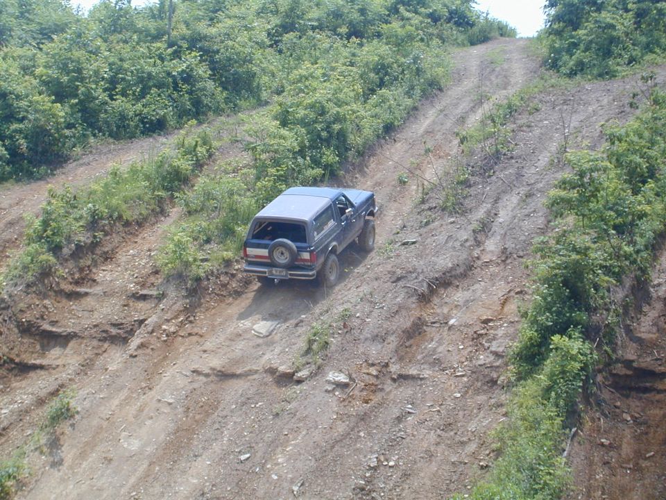 Dark blue SUV descending steep rutted dirt trail on eroded hillside