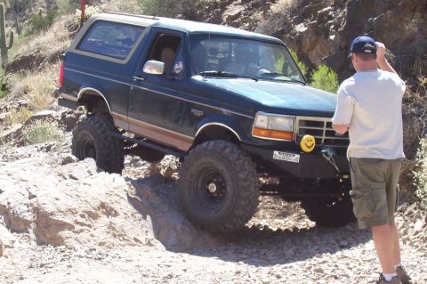 1992 Ford Bronco - This lifted Ford Bronco is tackling a challenging rocky terrain in a desert environment.