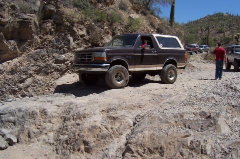 1992 Ford Bronco - This 1992 Ford Bronco navigates a desert trail, with other vehicles visible in the background.
