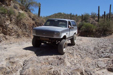 1992 Ford Bronco - This two-tone Ford Bronco navigates a desert path with saguaro cacti in the background.