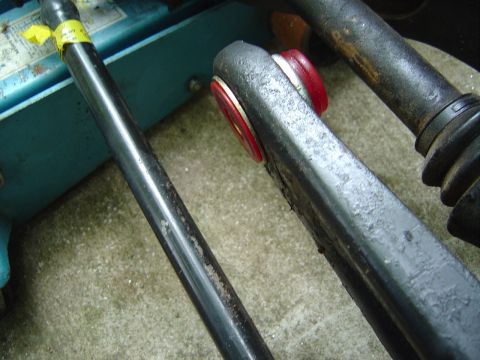 1986 Ford Bronco - Close-up of automotive tools and hardware, including a yellow-taped breaker bar or torque wrench handle and a heavy black steel component w…