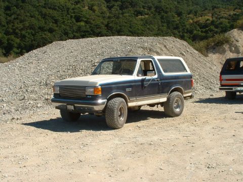 1990 Ford Bronco - This Ford Bronco is parked on a dirt road with a large pile of gravel in the background.