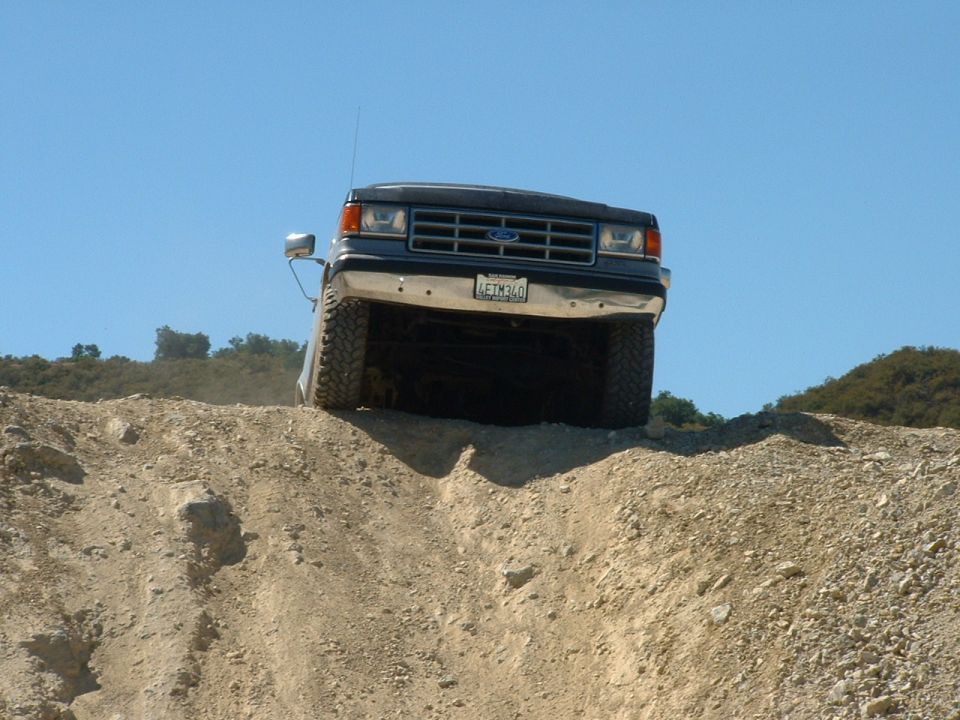 1990 Ford Bronco climbing a dirt hill, front view