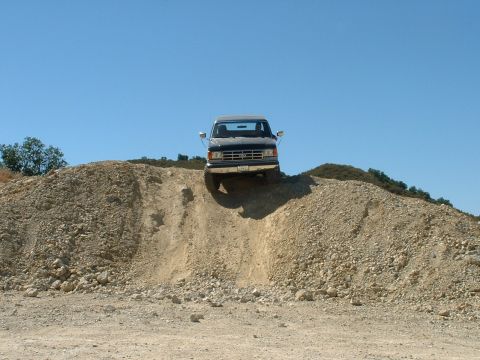 1990 Ford Bronco - Ford Bronco navigates a challenging incline on a dirt hill.