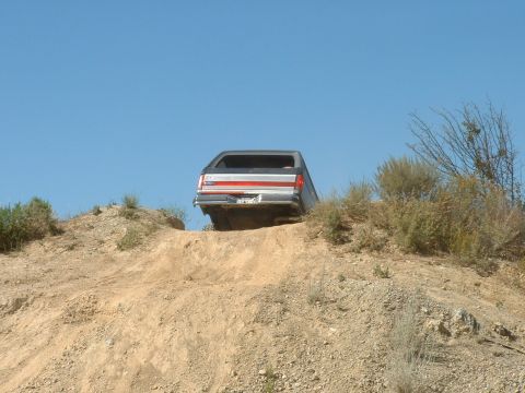 1990 Ford Bronco - 1990 Ford Bronco navigates an off-road trail on a sunny day.