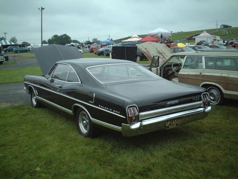1967 Ford Galaxie - A black 1967 Ford Galaxie 500 is displayed at an outdoor event with its hood open.