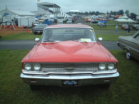 1967 Ford Galaxie - A red 1967 Ford Galaxie is displayed at an outdoor car show with other vehicles and tents in the background.