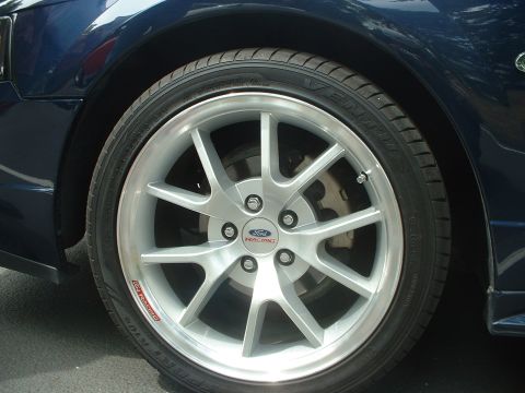 1999 Ford Crown Victoria - Close-up of a Ford Racing wheel on a dark blue vehicle, with visible tire tread and brake components.