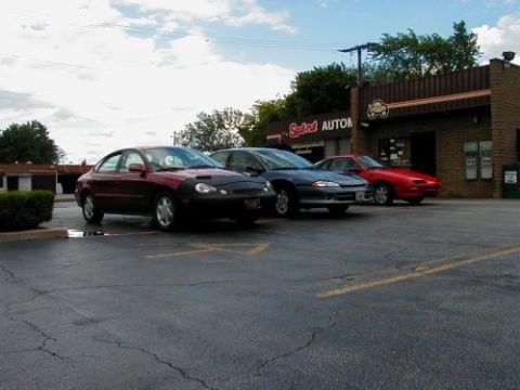 1997 Ford Taurus - A 1997 Ford Taurus is parked in front of an auto shop alongside two other vehicles.