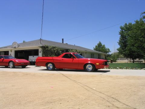 1974 Ford Ranchero - A red 1977 Ford Ranchero is parked in front of a house, with another red car to its left.