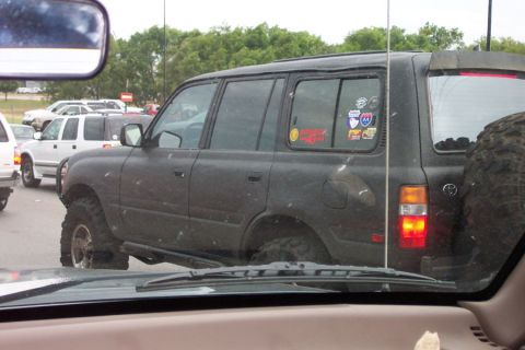 1992 Ford Bronco - This dark SUV features off-road tires and several stickers on its rear window, suggesting a customized build.