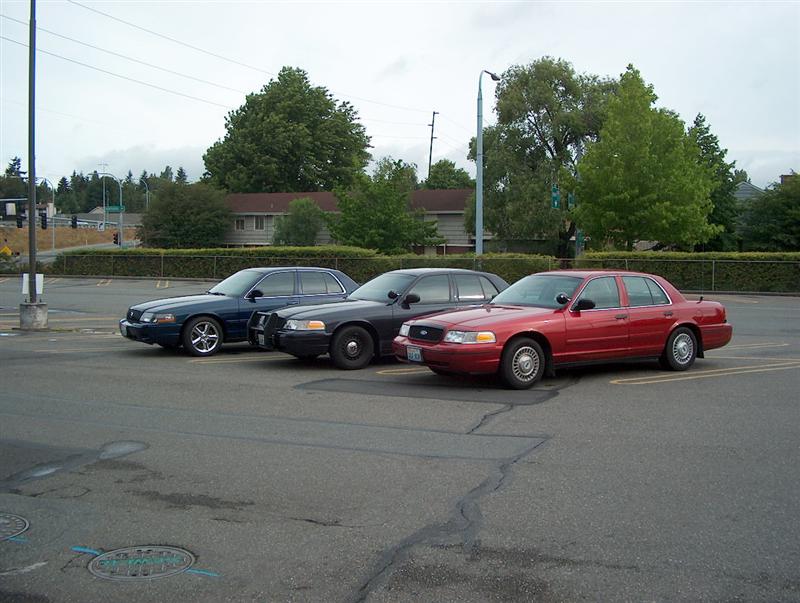 Red, black and dark blue Ford sedans parked side by side in an empty lot
