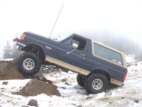 1991 Ford Bronco - Ford Bronco navigating rocky terrain in snowy conditions.