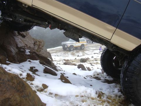 1991 Ford Bronco - Two Broncos navigate a challenging, snow-covered mountain path.