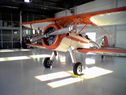 1998 Ford Crown Victoria - A biplane with orange and cream paint is parked inside a hangar.