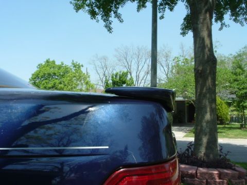 1993 Ford Taurus - Rear spoiler on a dark blue car, seen from a low angle on a sunny day.