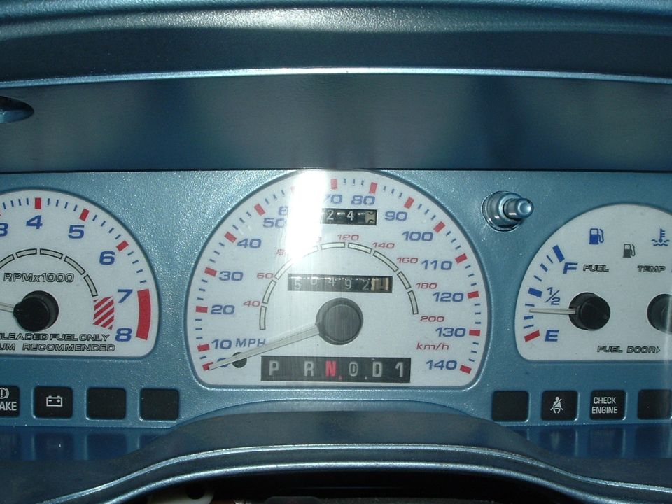 Close-up of a car's dashboard gauges, including speedometer, tachometer, fuel, and temperature gauges