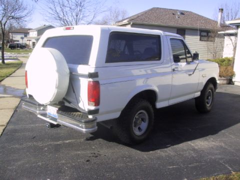 1993 Ford Bronco - This white Ford Bronco is parked in a suburban driveway with a house in the background.
