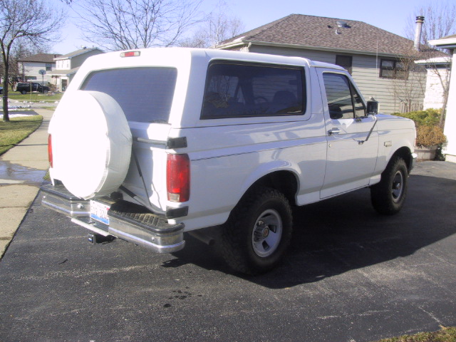 white Ford Bronco parked in driveway, spare tire on back