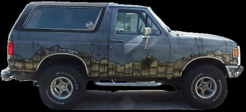1989 Ford Bronco - Side profile of a two-door Ford Bronco SUV in dark green/black with a custom airbrushed rock or stone graphic along the lower body panels.…