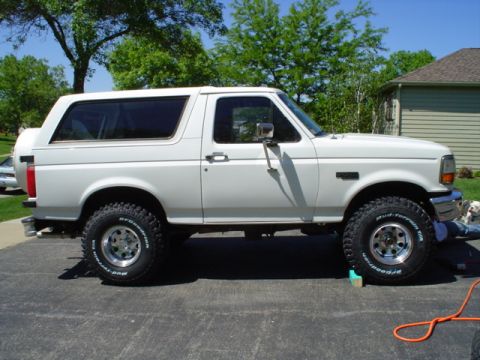1993 Ford Bronco - A white two-door Ford Bronco full-size SUV shown in side profile, parked on a paved driveway with a lift kit and BFGoodrich all-terrain tir…