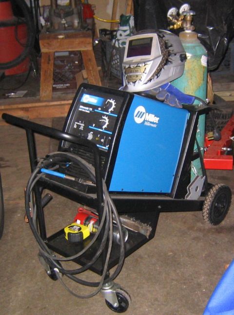 1978 Ford Bronco - A Miller welding machine is shown with a helmet resting on top, next to a gas cylinder.