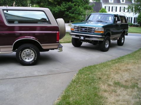 1996 Ford Bronco - Two Ford Broncos, a green 1996 model and a maroon one, are parked on a driveway.