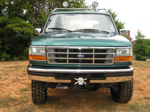 1996 Ford Bronco - A lifted 1996 Ford Bronco is shown from the front, equipped with auxiliary lights and a decorative license plate frame.