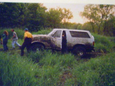 1993 Ford Bronco - This vehicle appears to be stuck in a muddy, grassy area with several people observing.
