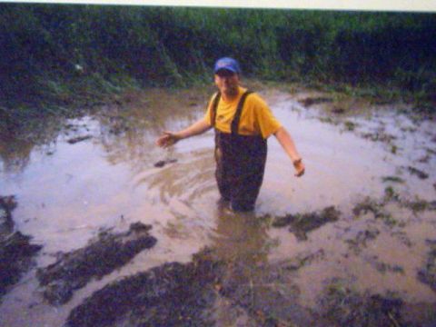 1993 Ford Bronco - A man stands in a muddy field, seemingly stuck or enjoying the mire.