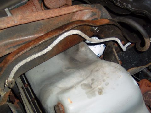 1993 Ford Bronco - Close-up view of the underside of a vehicle, focusing on the oil pan and surrounding rusty metal parts.