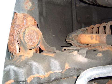 1993 Ford Bronco - Close-up view of heavily rusted suspension components on a vehicle's undercarriage.