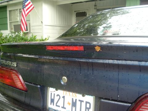 1993 Ford Taurus - Rear view of a dark 1993 Ford Taurus sedan, showing the taillights and license plate.