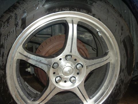 1993 Ford Taurus - Aftermarket wheel with 'NSR' center cap and a worn tire. Rusty brake rotor is visible.
