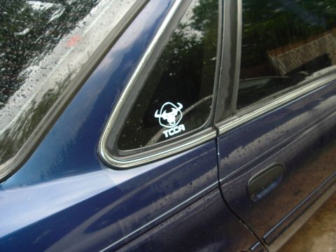 1993 Ford Taurus - A sticker with a bull logo and "TCCA" is visible on the rear passenger window of a blue sedan.