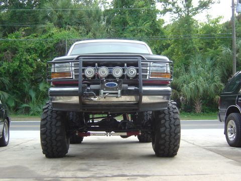 1993 Ford Bronco - This heavily modified pickup truck features a prominent bull bar with auxiliary lights and oversized off-road tires.