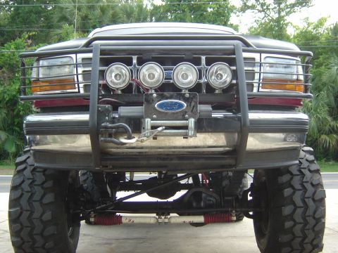 1993 Ford Bronco - Front view of a modified black Ford Bronco with a bull bar and winch, large off-road tires.