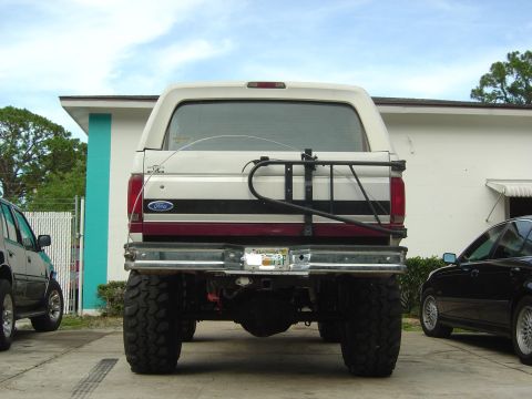 1993 Ford Bronco - Rear view of a lifted 1993 Ford Bronco, showing its spare tire carrier and custom wheels.